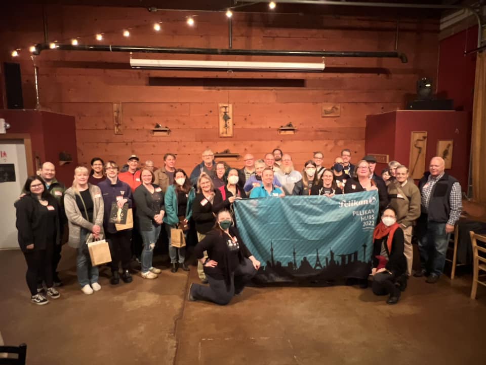 group photo of about 40 people, holding a blue Pelikan hub banner