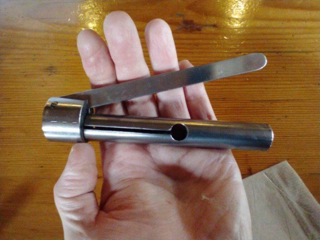 a hand holding a cylindrical clamp tools used to pull feeds from fountain pens